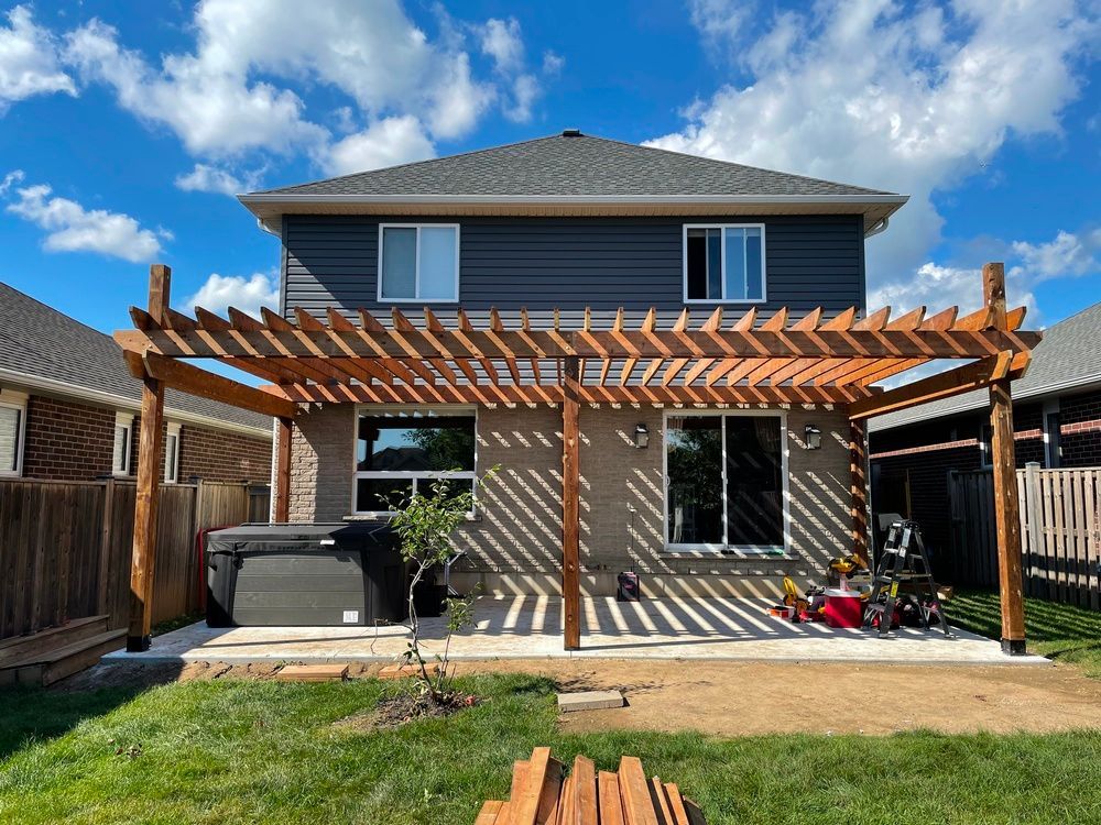 The backyard of a house with a pergola and a hot tub.
