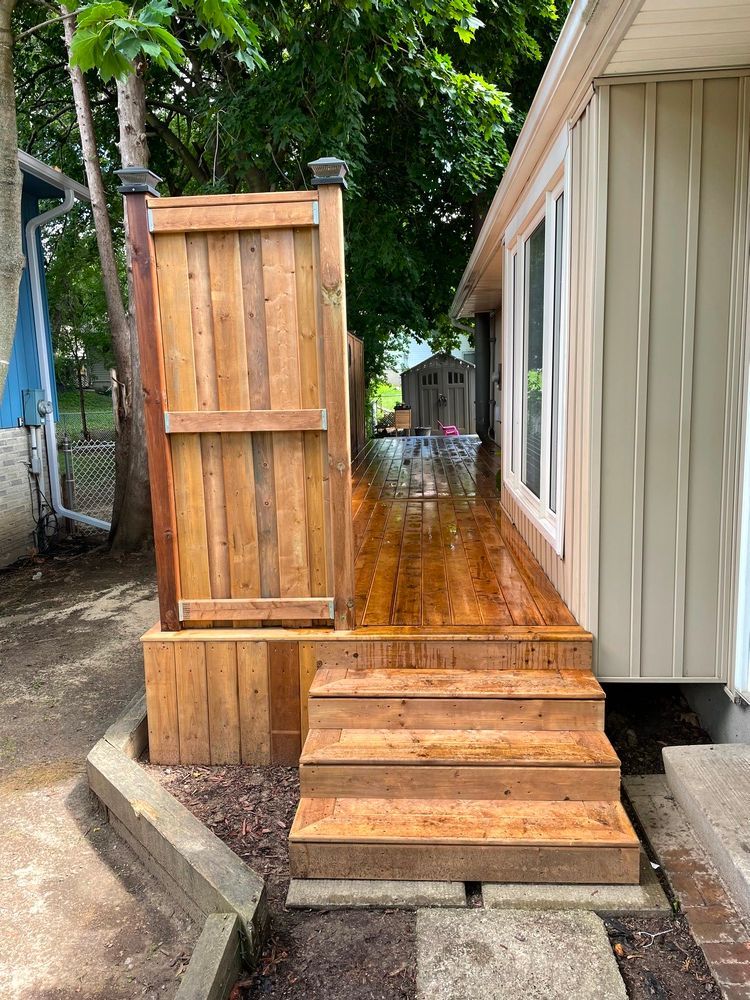 A wooden deck with stairs and a wooden fence in front of a house.
