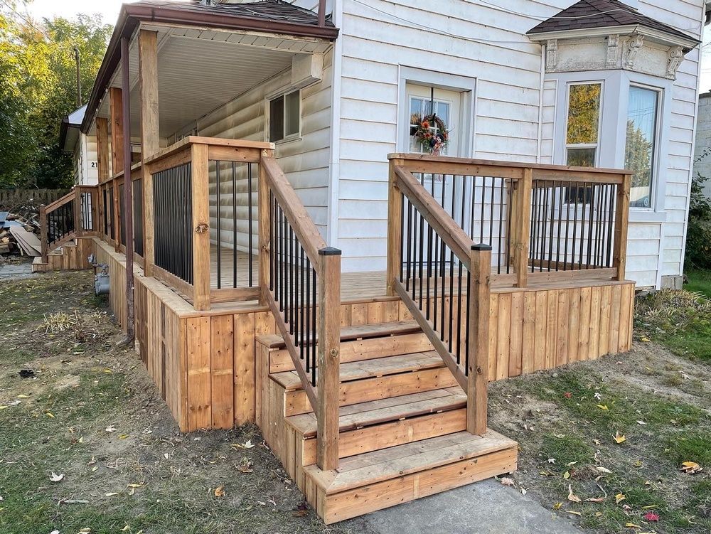 A wooden deck with stairs is in front of a white house.