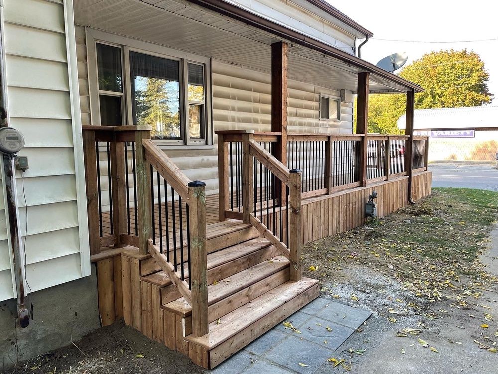 A wooden deck with stairs leading up to it is in front of a house.