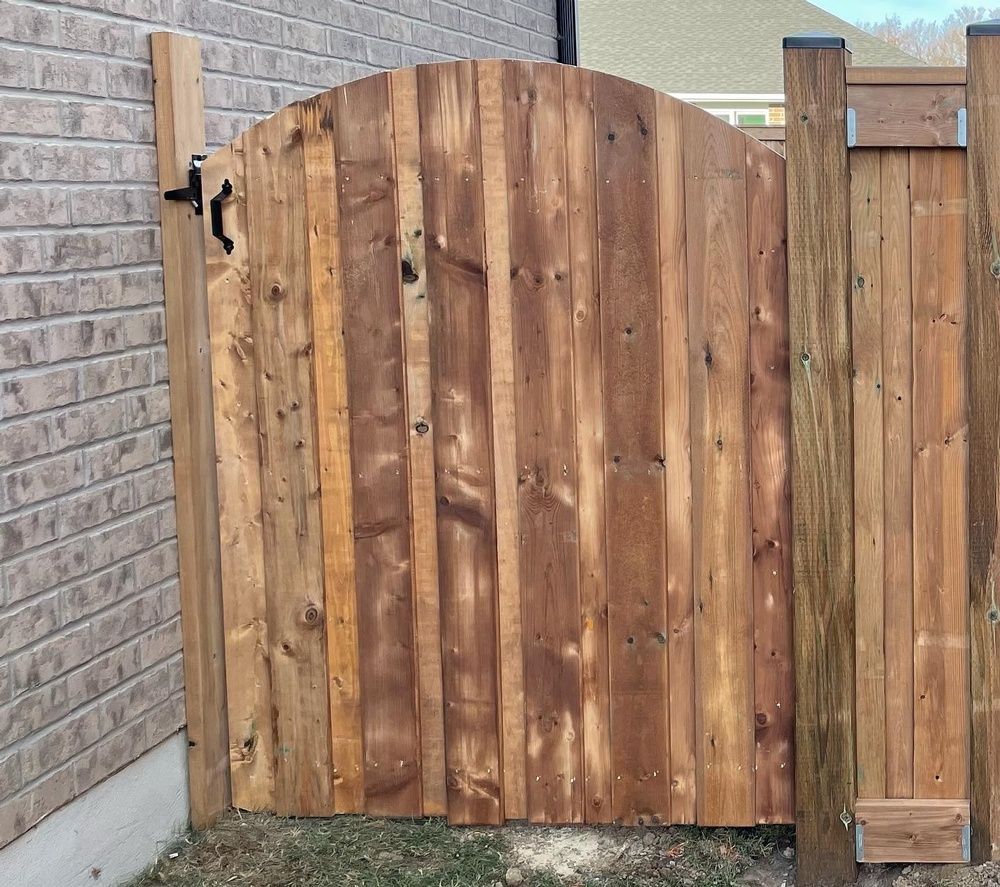 A wooden gate with a brick wall in the background