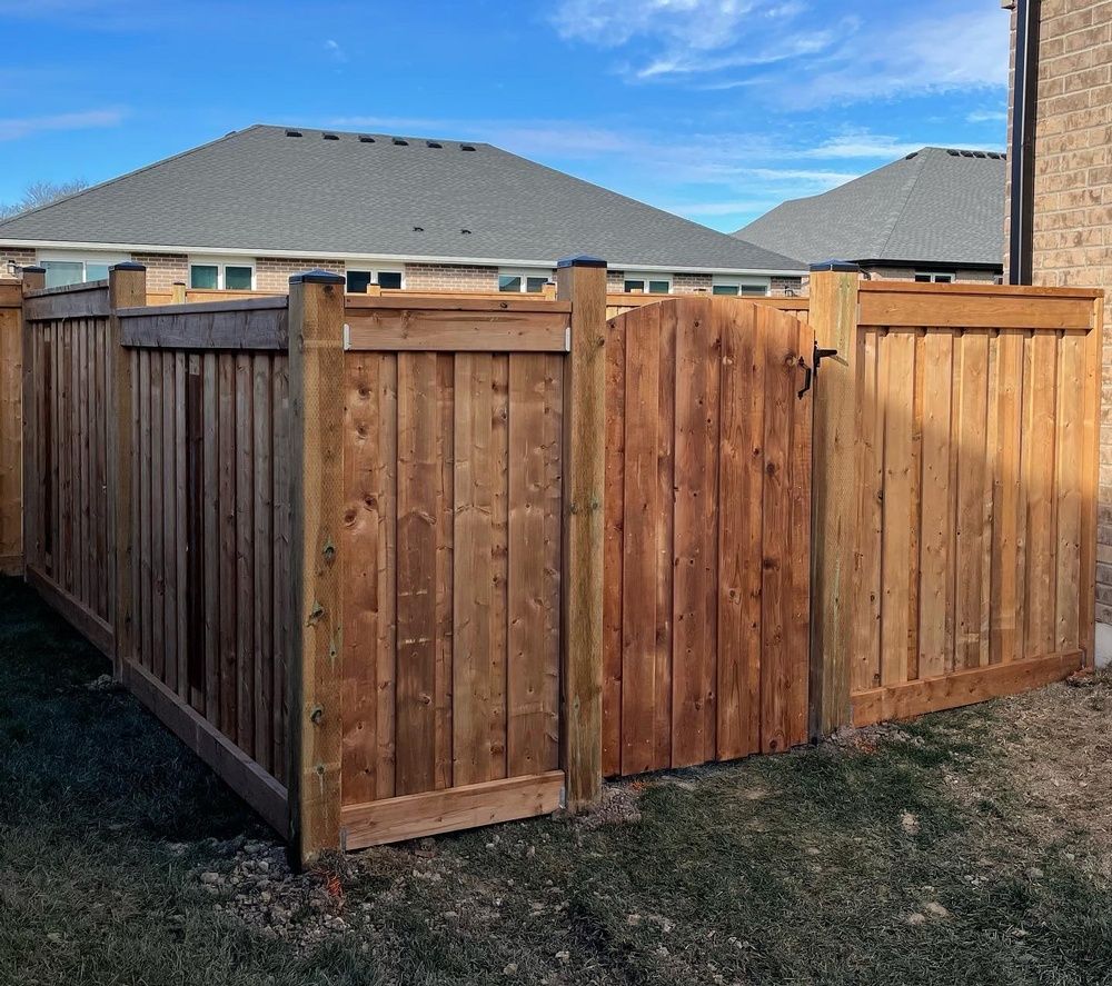 A wooden fence with a gate in the backyard of a house.