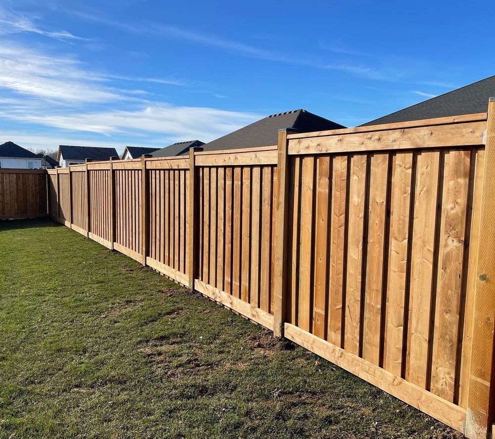 A wooden fence is sitting in the middle of a lush green field.