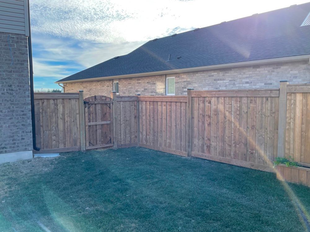 A wooden fence with a gate in the backyard of a house.