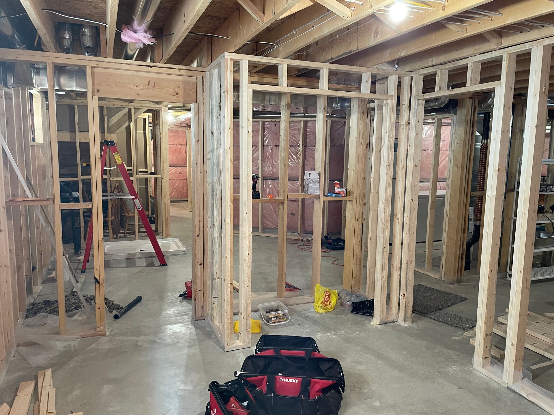 A basement under construction with a tool bag on the floor.