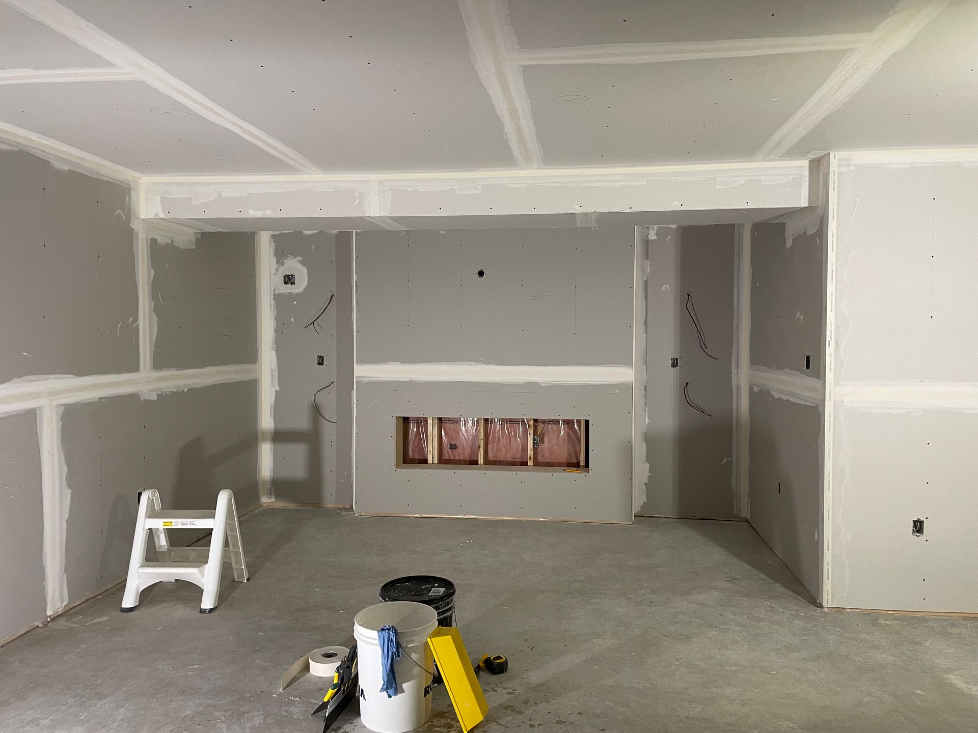 A room with drywall walls and a ladder in it.