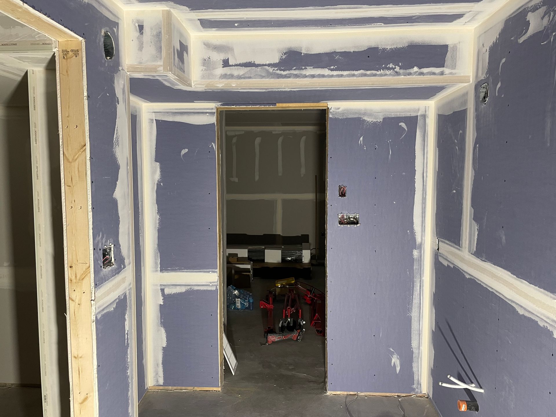 A room with purple walls and white trim is being remodeled