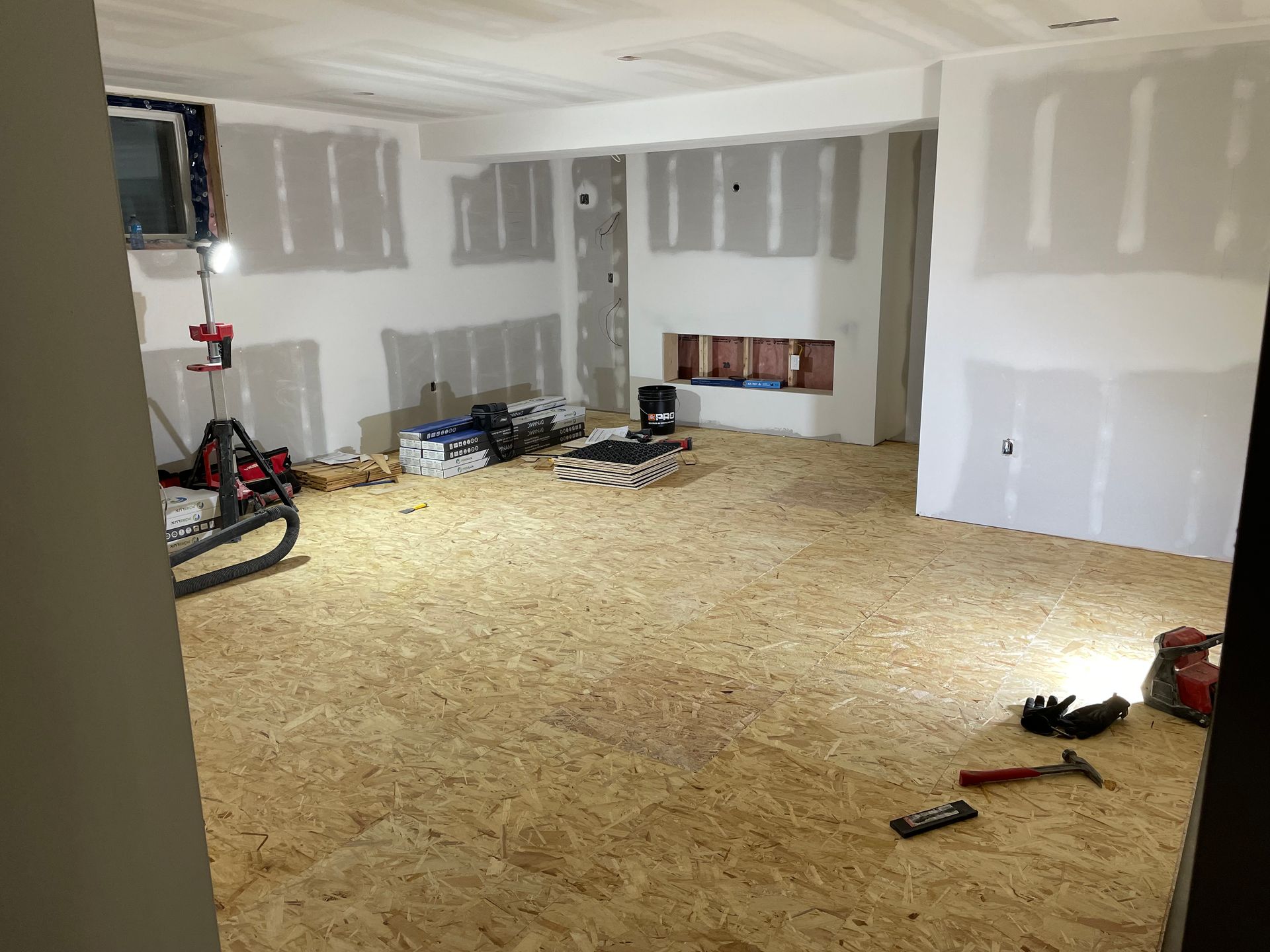 A room with a wooden floor and white walls is being remodeled.
