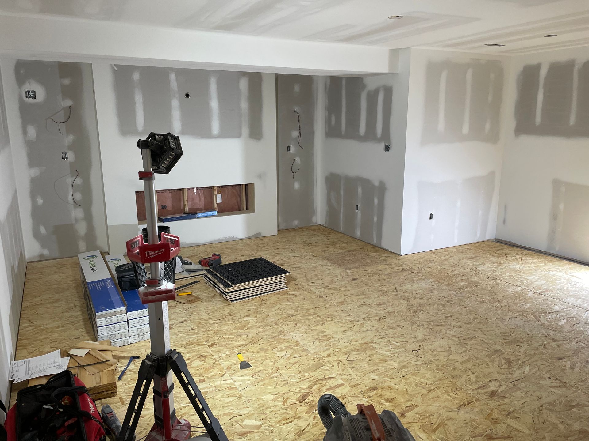 A room with a wooden floor and white walls is being remodeled.