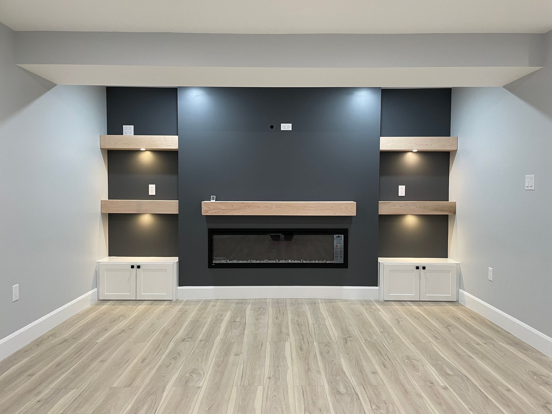 An empty living room with a fireplace and shelves.