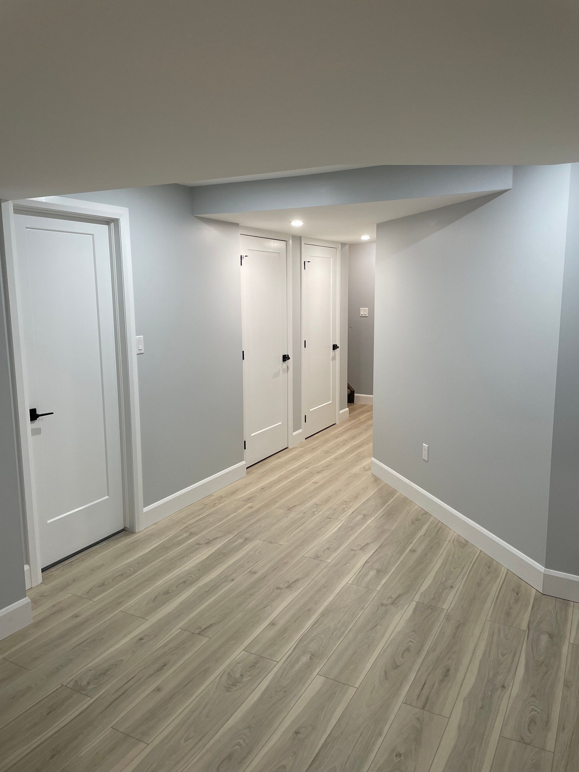 An empty room with hardwood floors and gray walls.