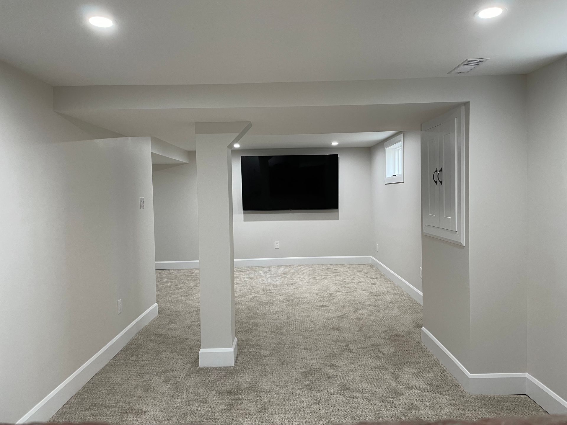 A basement with a flat screen tv on the wall.