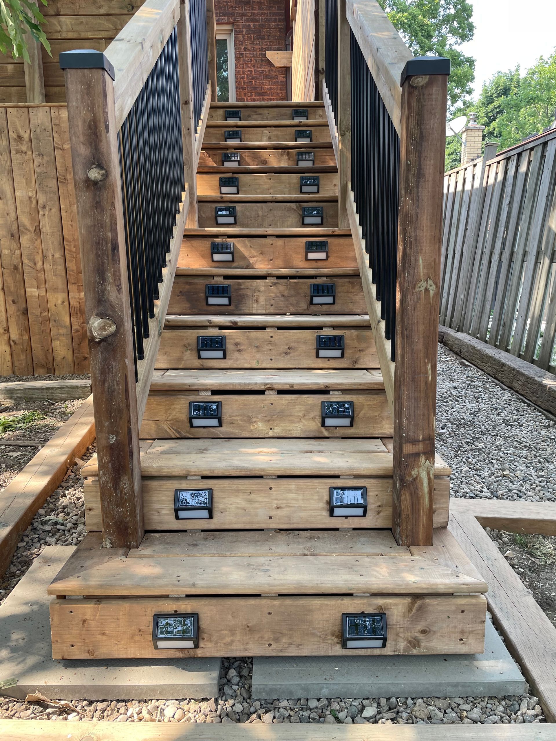 A wooden deck with stairs and a black railing