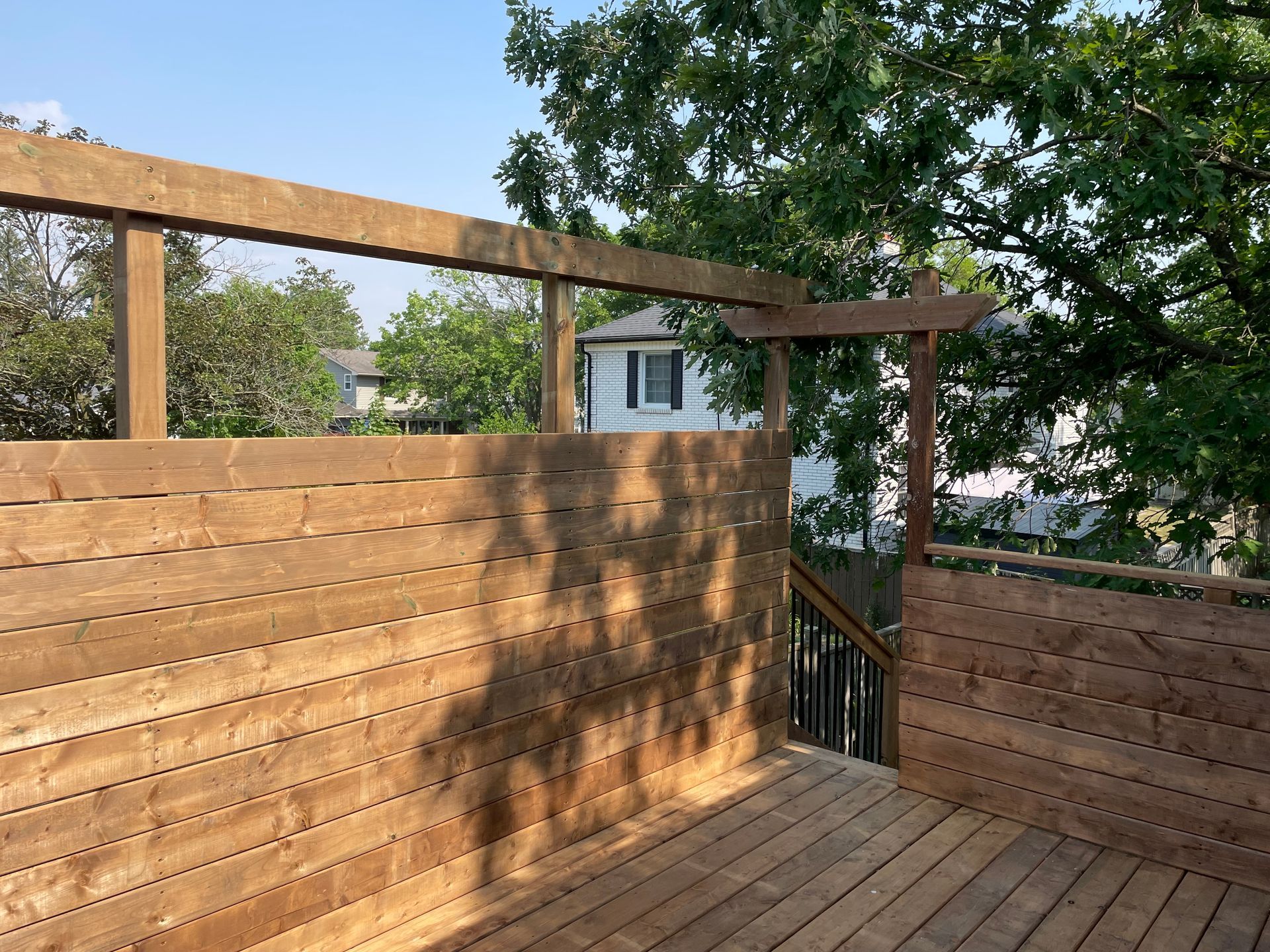 A wooden deck with a fence and stairs in the background