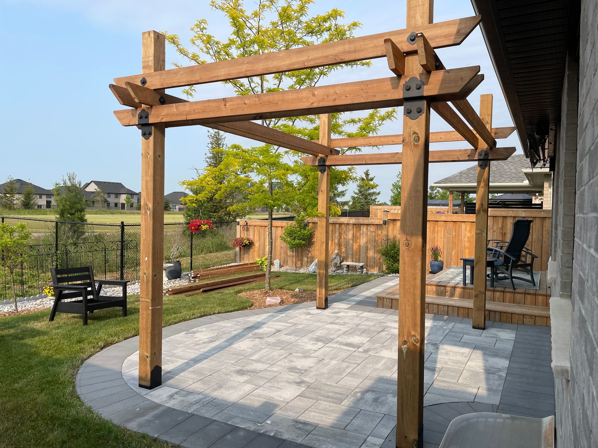 A wooden pergola is sitting on top of a patio in a backyard.