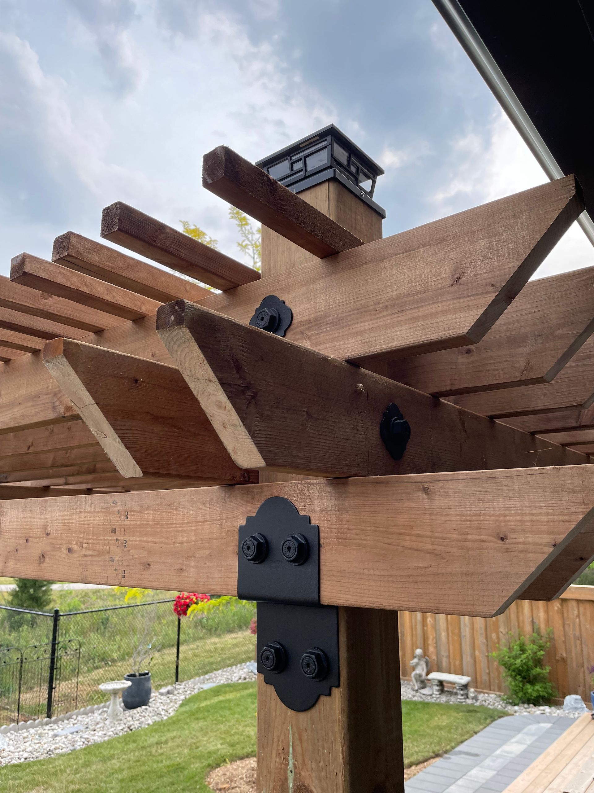 A wooden pergola with a chimney on top of it in a backyard.