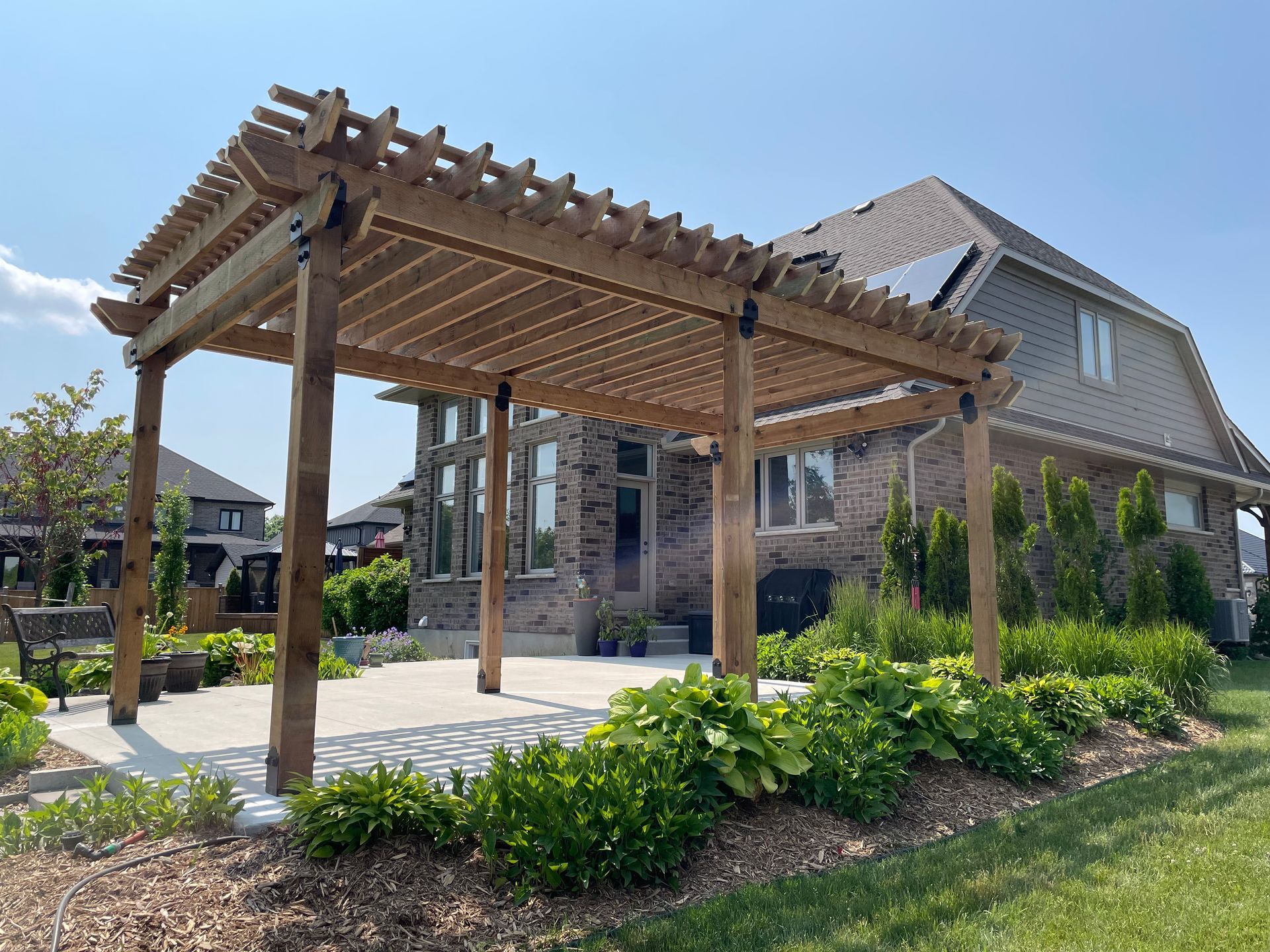 A large house with a wooden pergola in front of it.