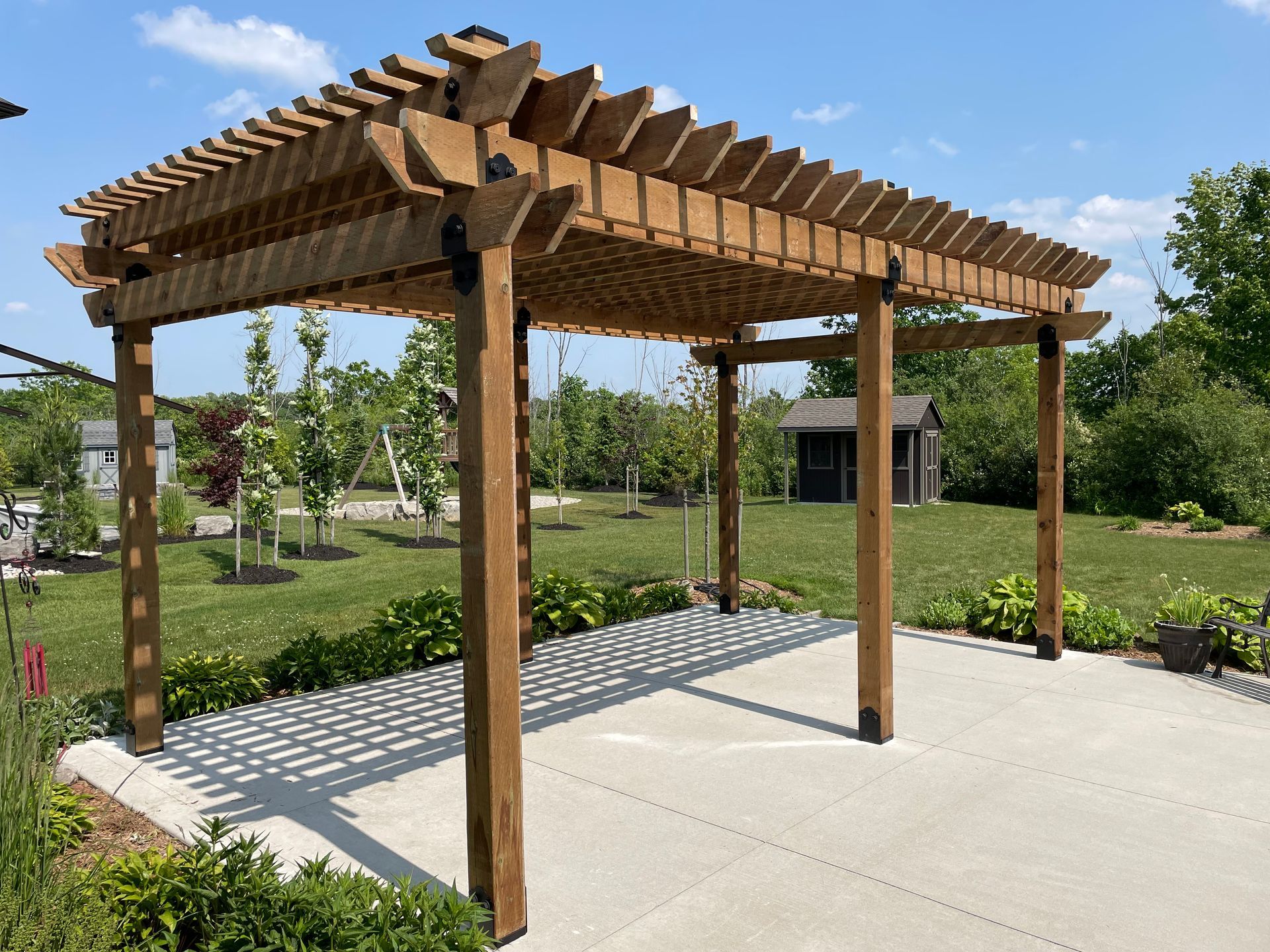A wooden pergola is sitting on top of a concrete patio.