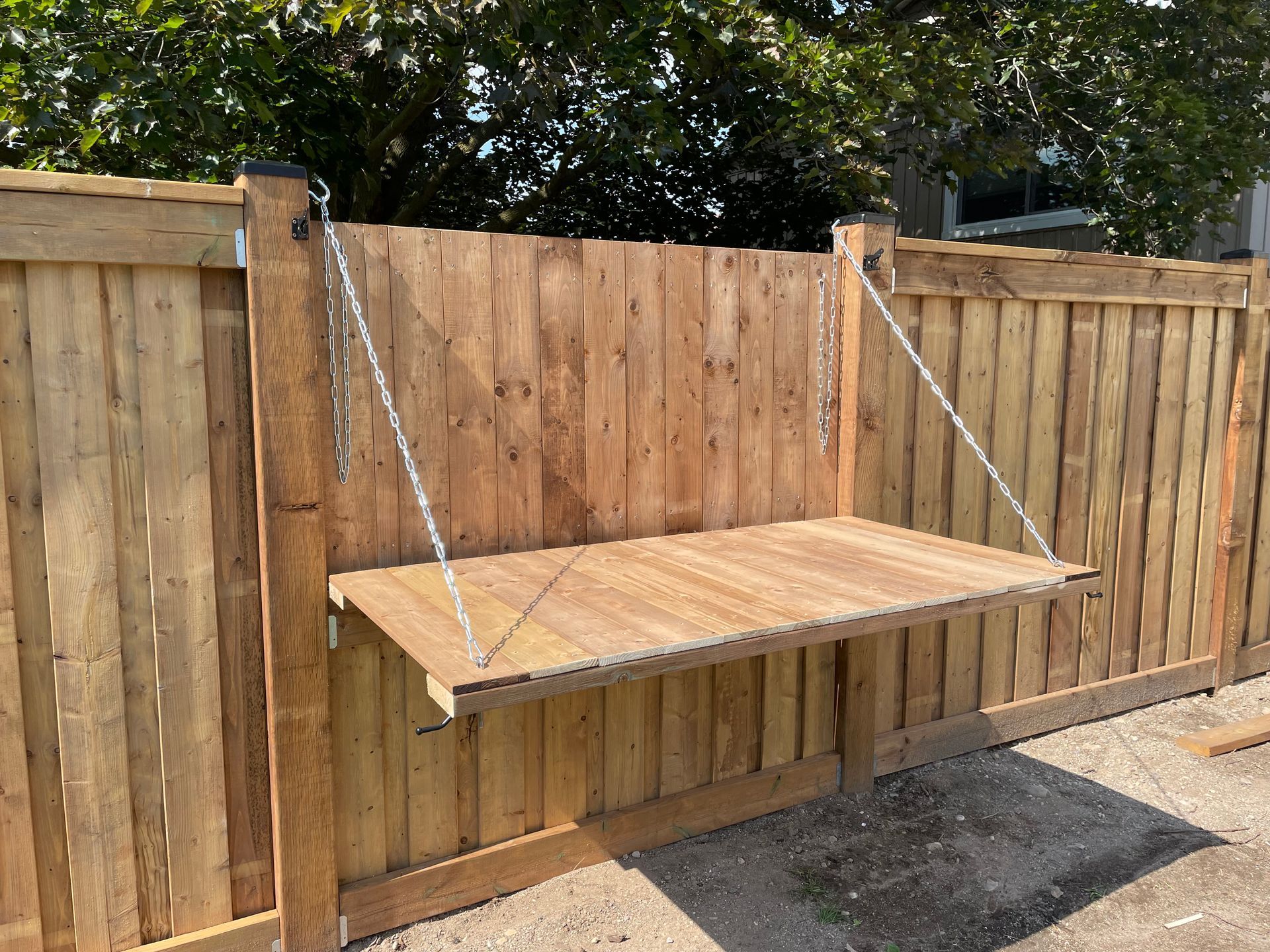 A wooden table is attached to a wooden fence.