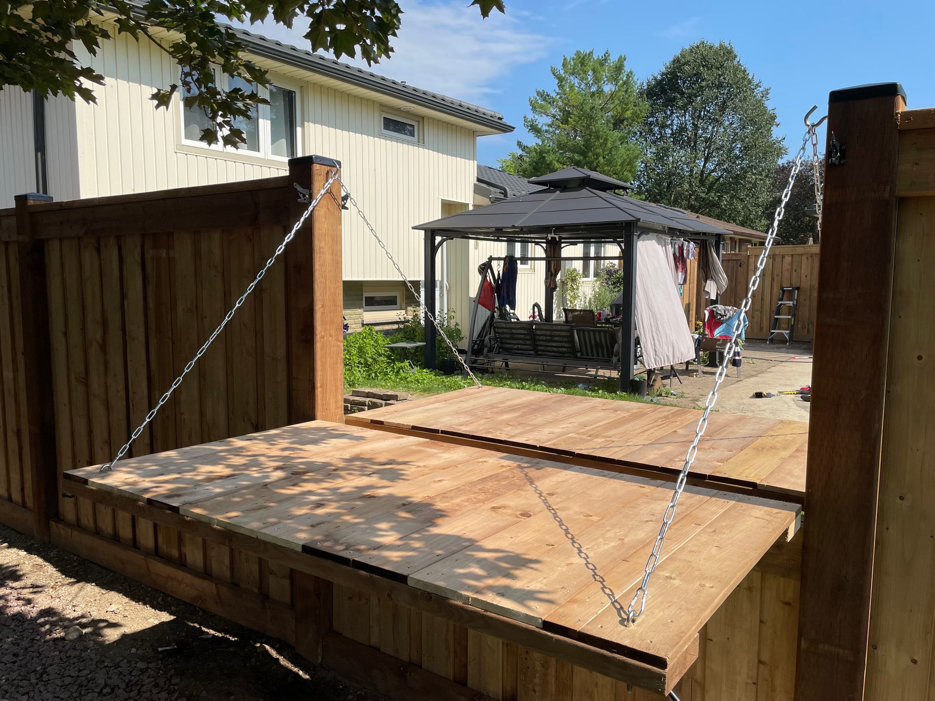 A wooden deck is being built in a backyard with a gazebo in the background.