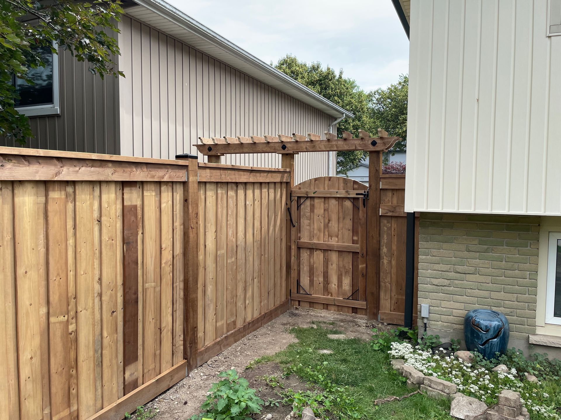 A wooden fence with a gate in the backyard of a house.