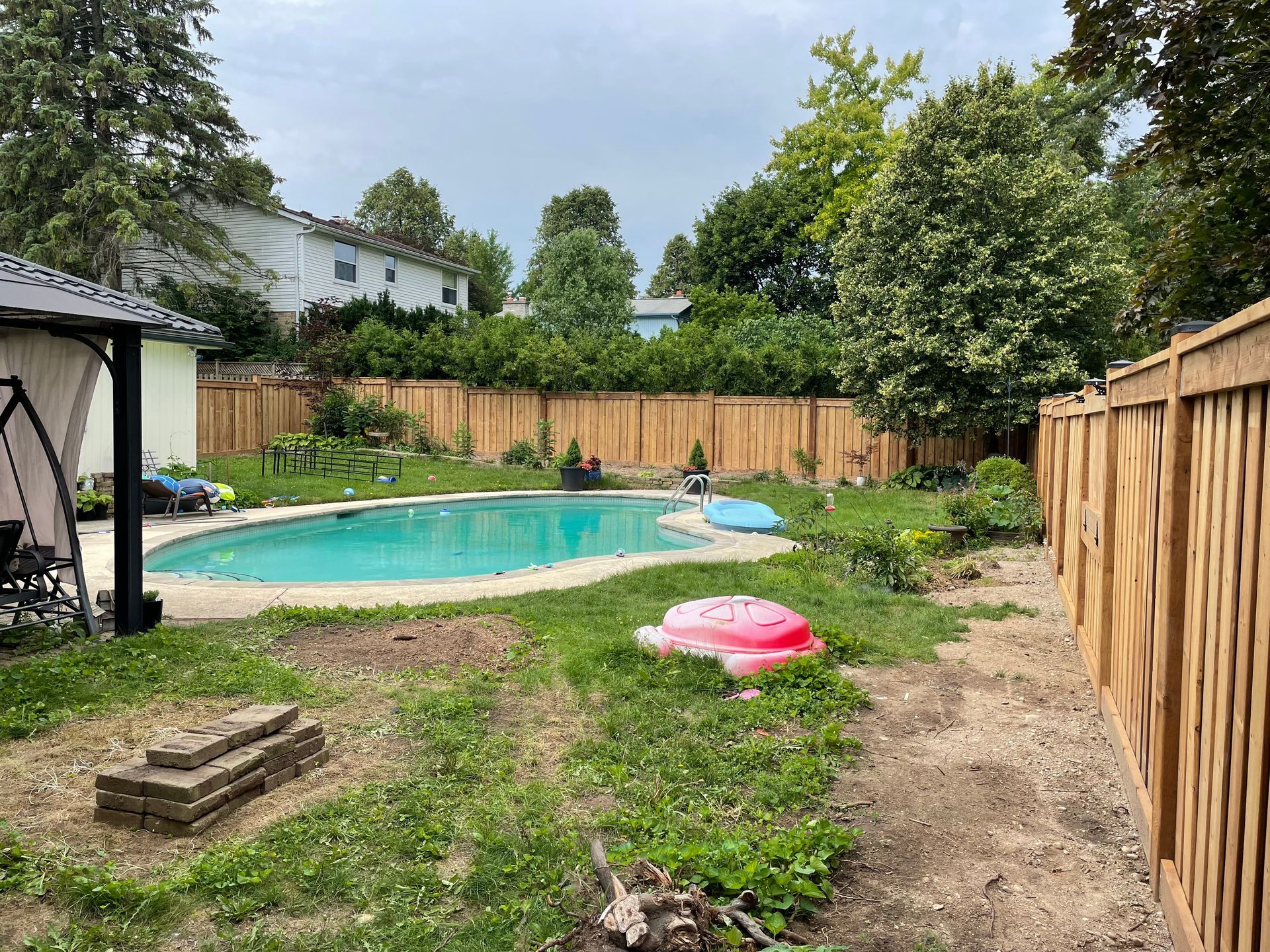 A backyard with a pool and a wooden fence.