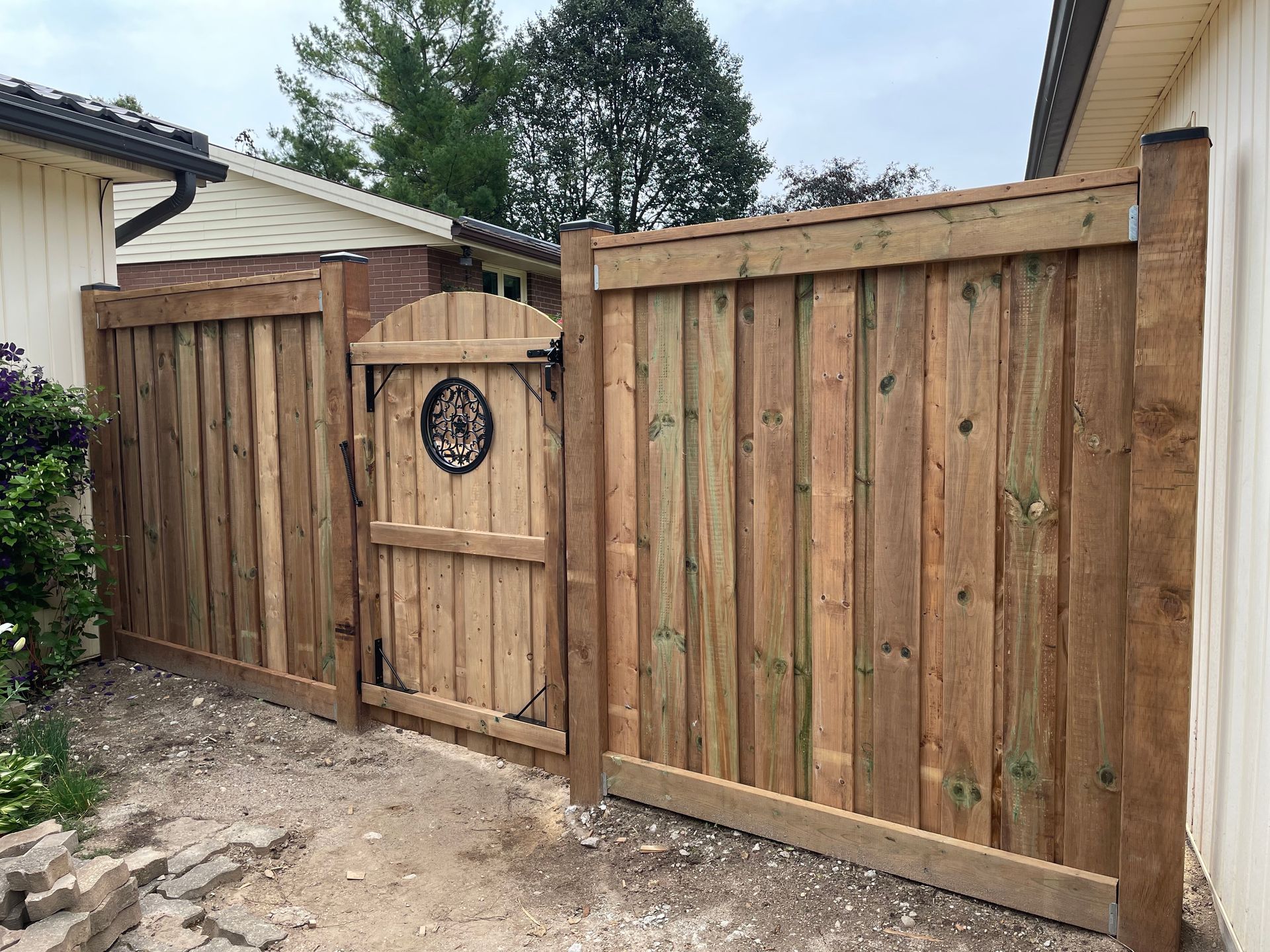A wooden fence with a gate in front of a house.