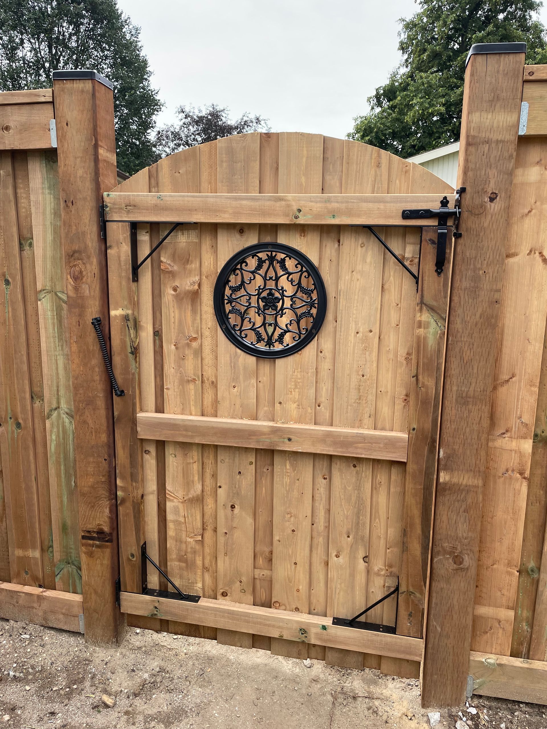 A wooden gate with a circular design on it is surrounded by a wooden fence.