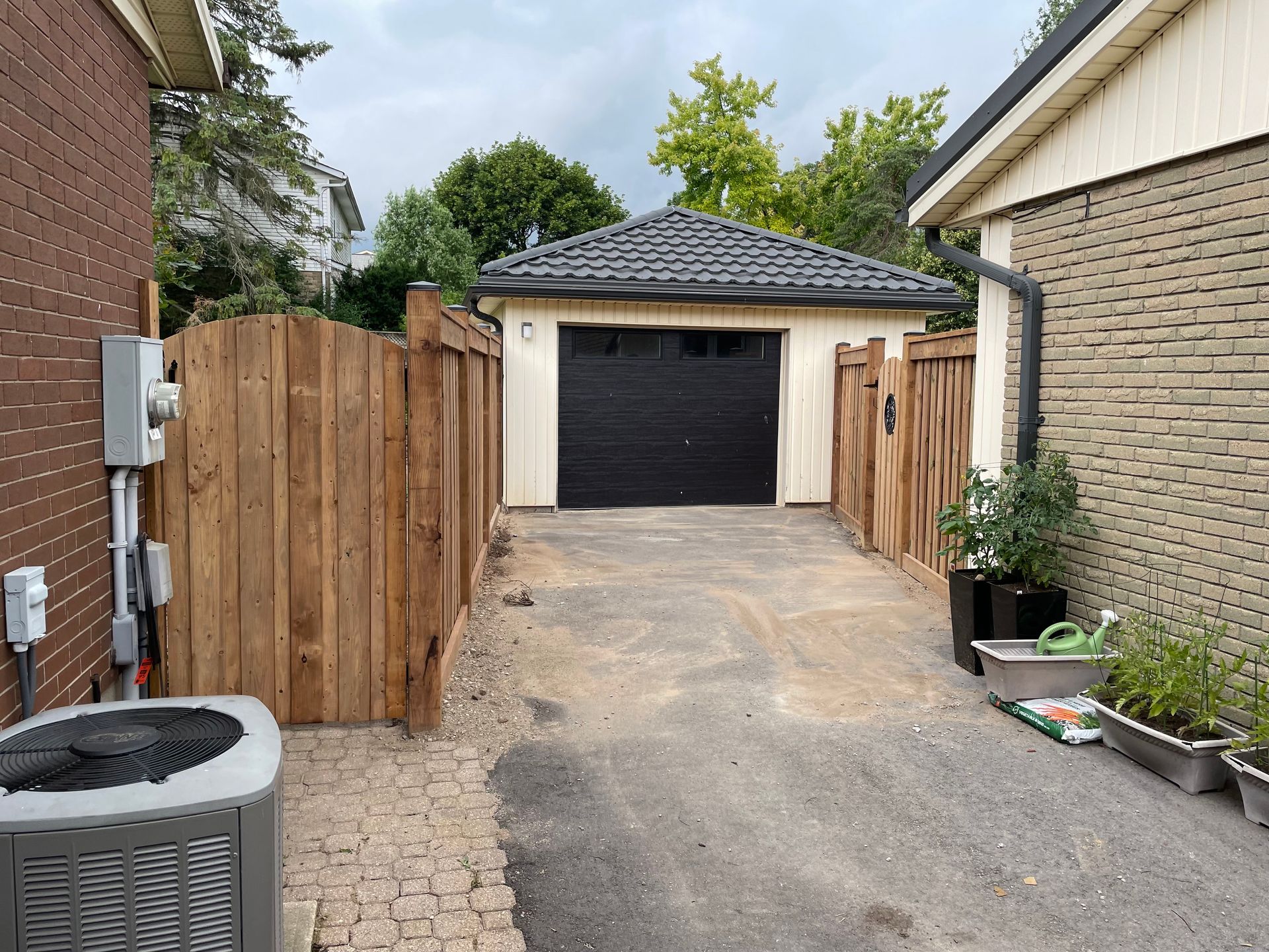 A wooden fence surrounds a driveway leading to a garage.