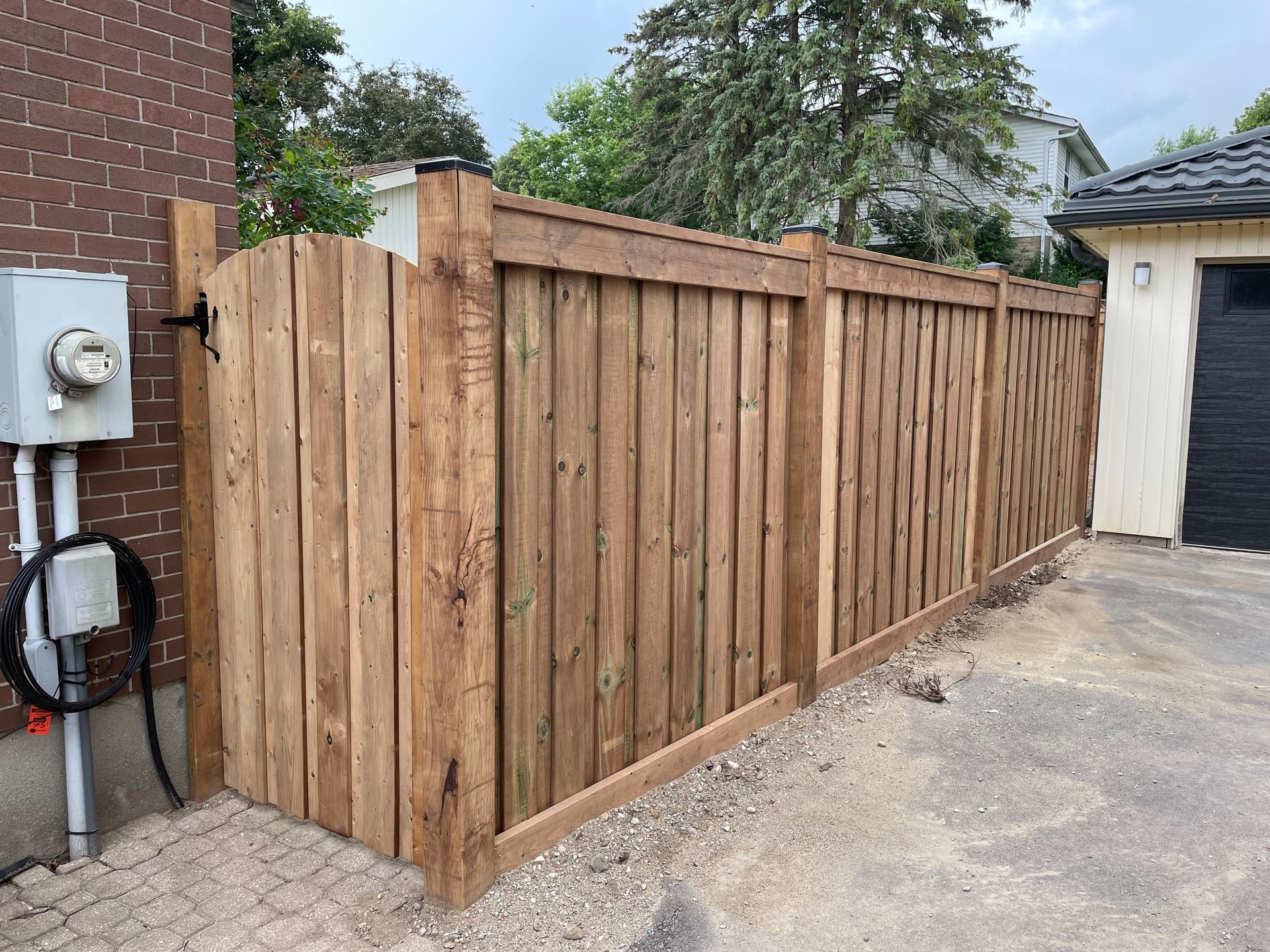 A wooden fence is sitting next to a brick building.