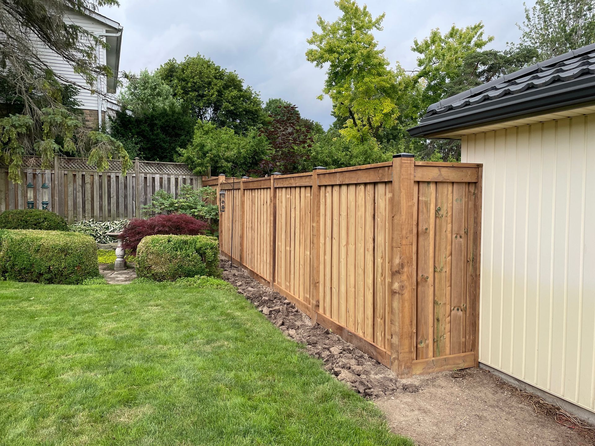 A wooden fence is in the backyard of a house.