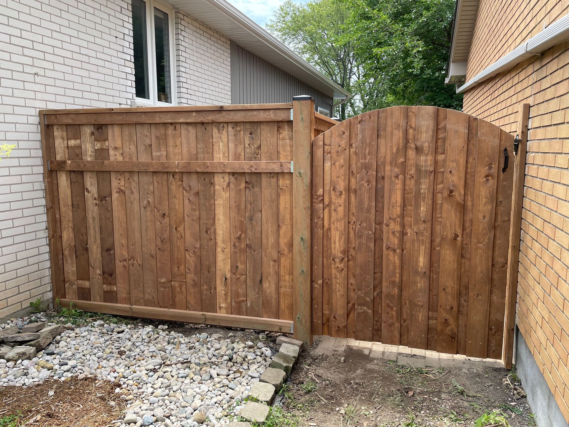 A wooden fence with a gate in front of a brick house.