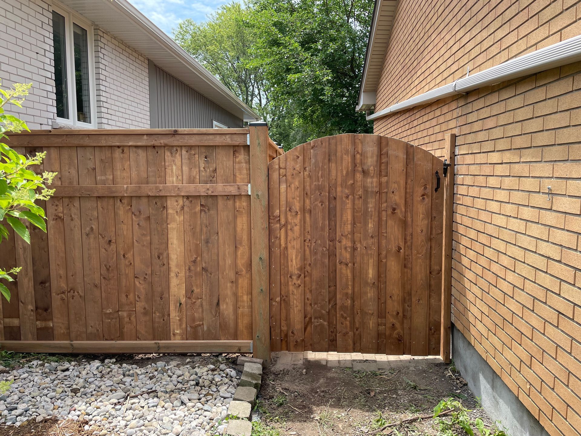 A wooden fence is sitting next to a brick building.