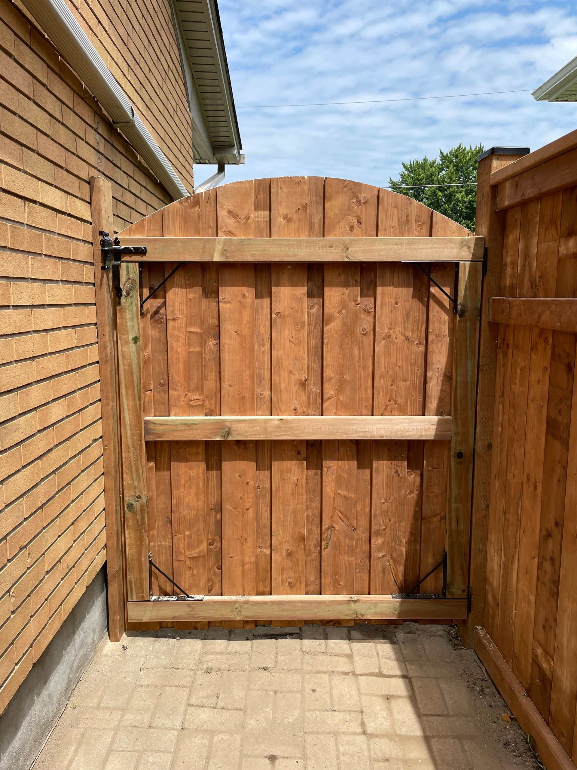 A wooden gate is between two brick buildings.