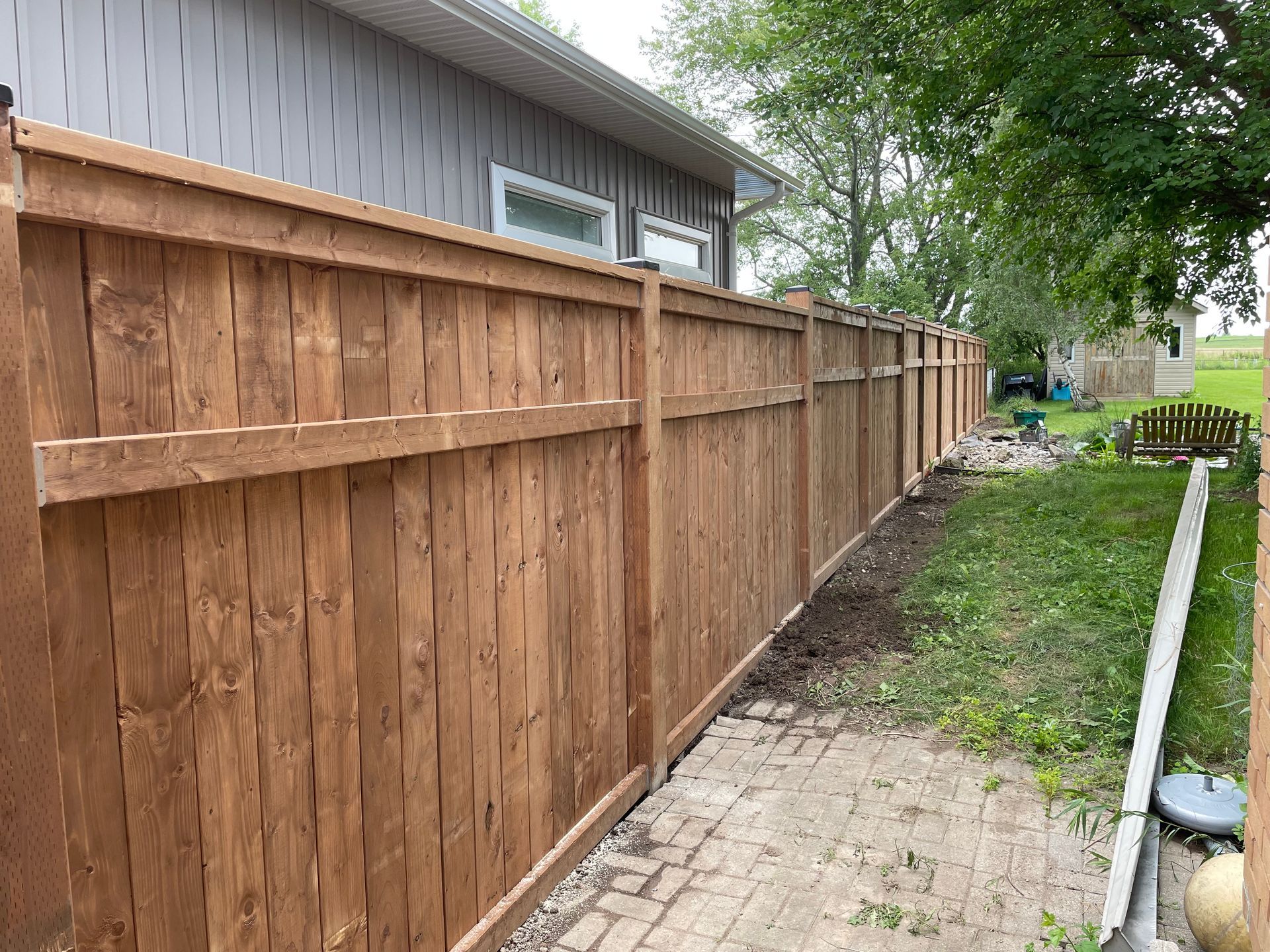 A wooden fence is in the backyard of a house.