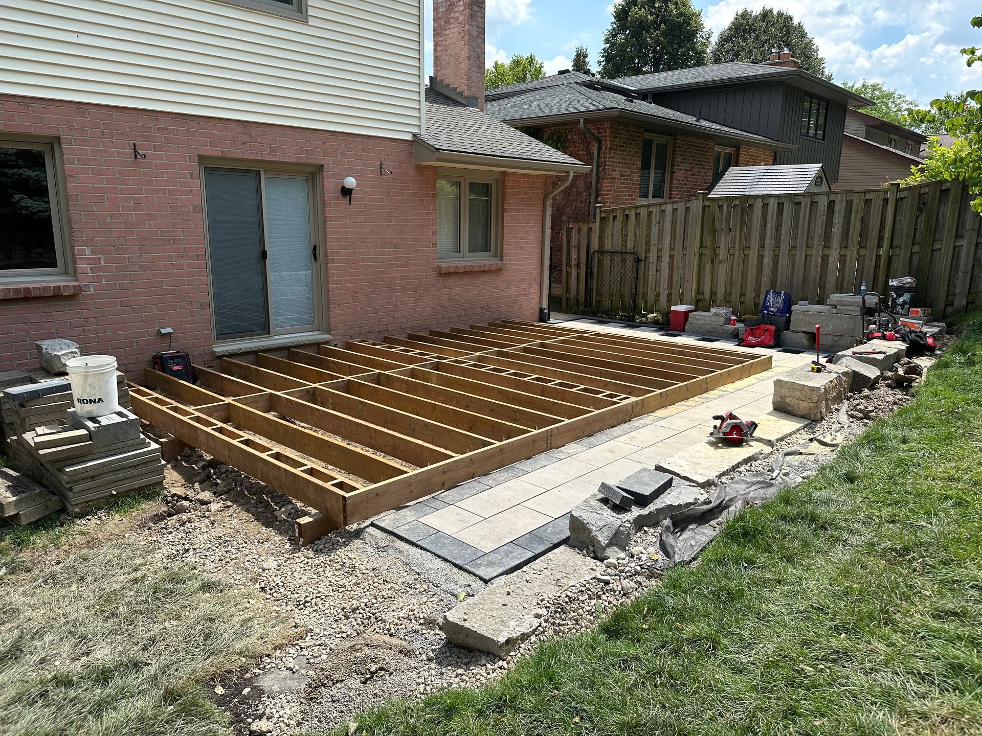 A wooden deck is being built in the backyard of a house.