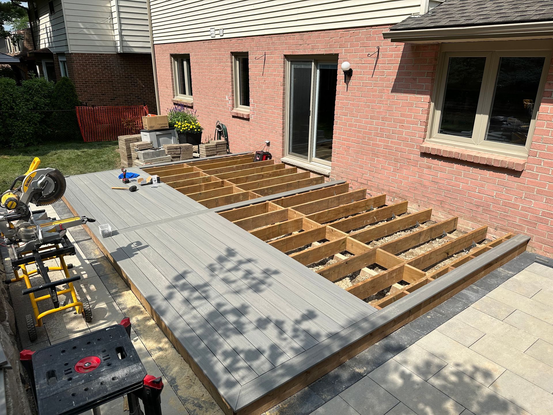 A wooden deck is being built in front of a brick house.