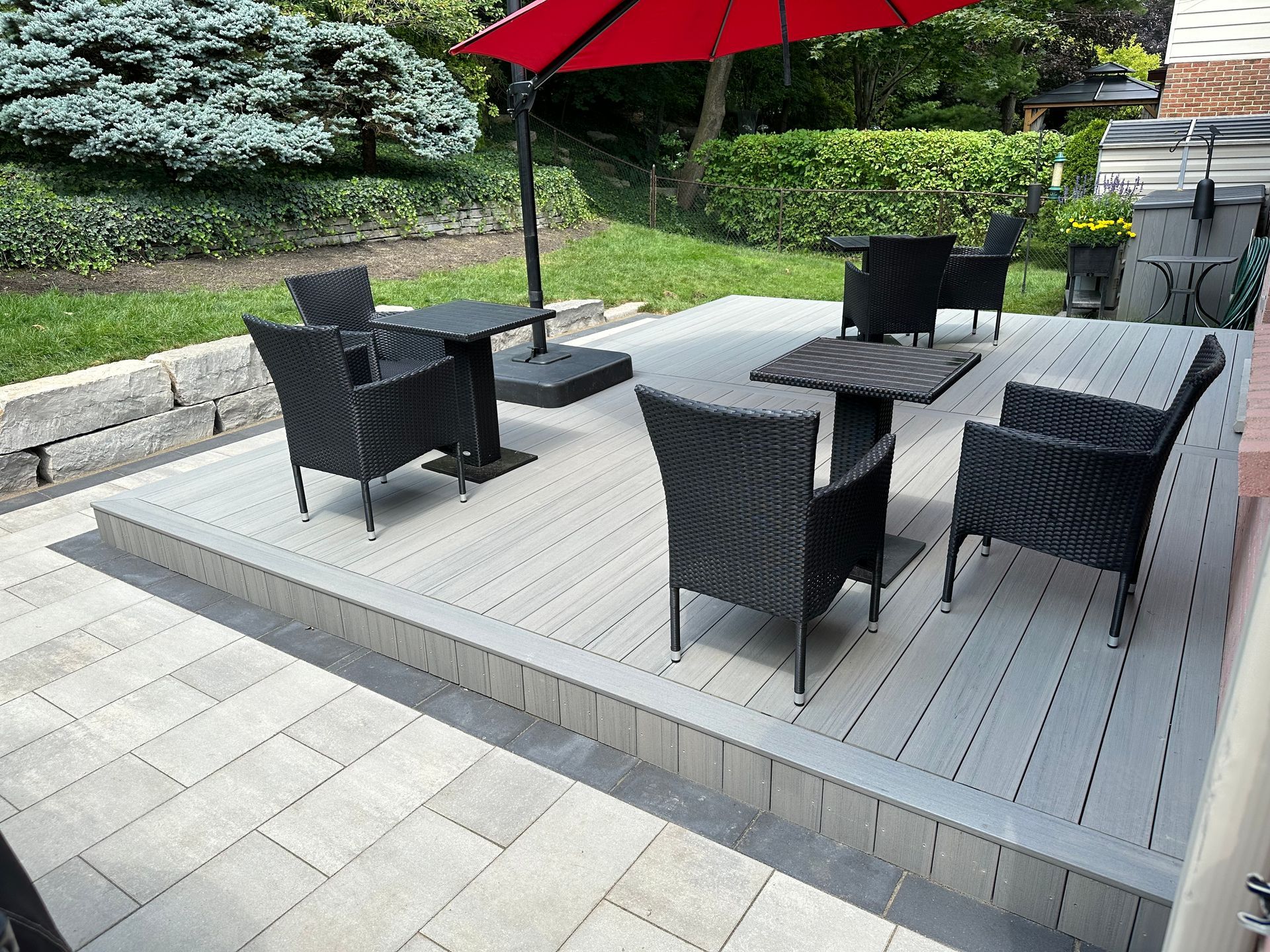 A patio with chairs and tables under an umbrella
