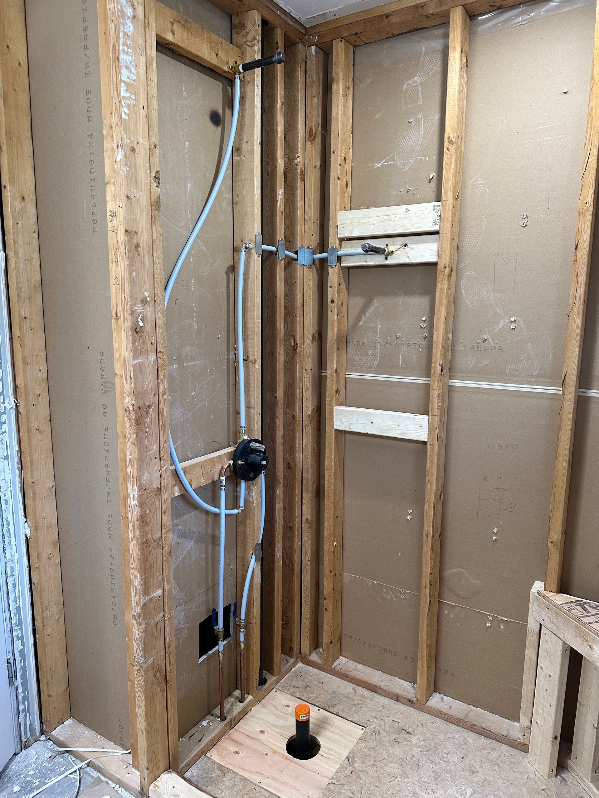 A bathroom under construction with wooden beams and pipes coming out of the wall.