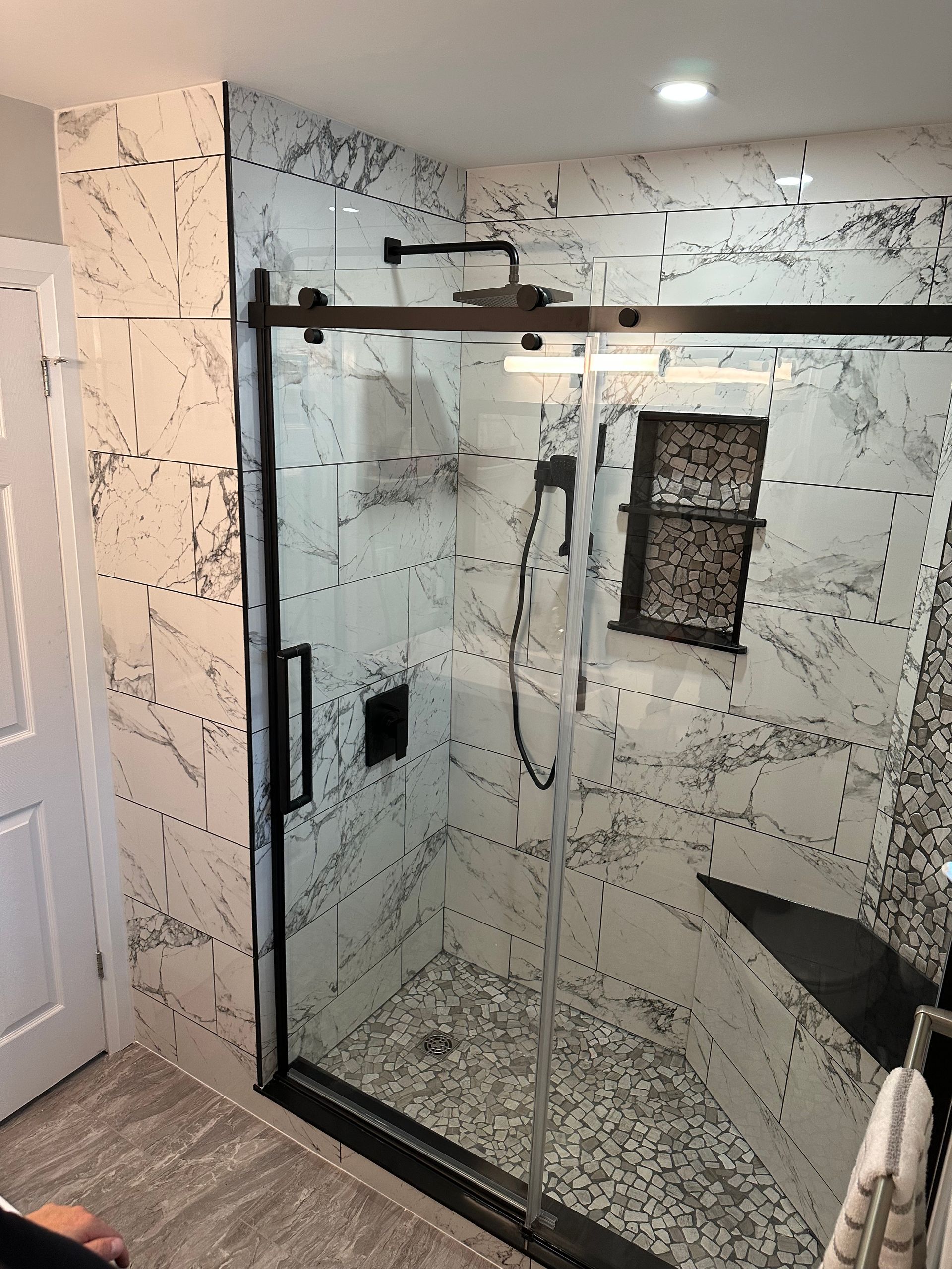 A bathroom with a sliding glass shower door and marble walls.