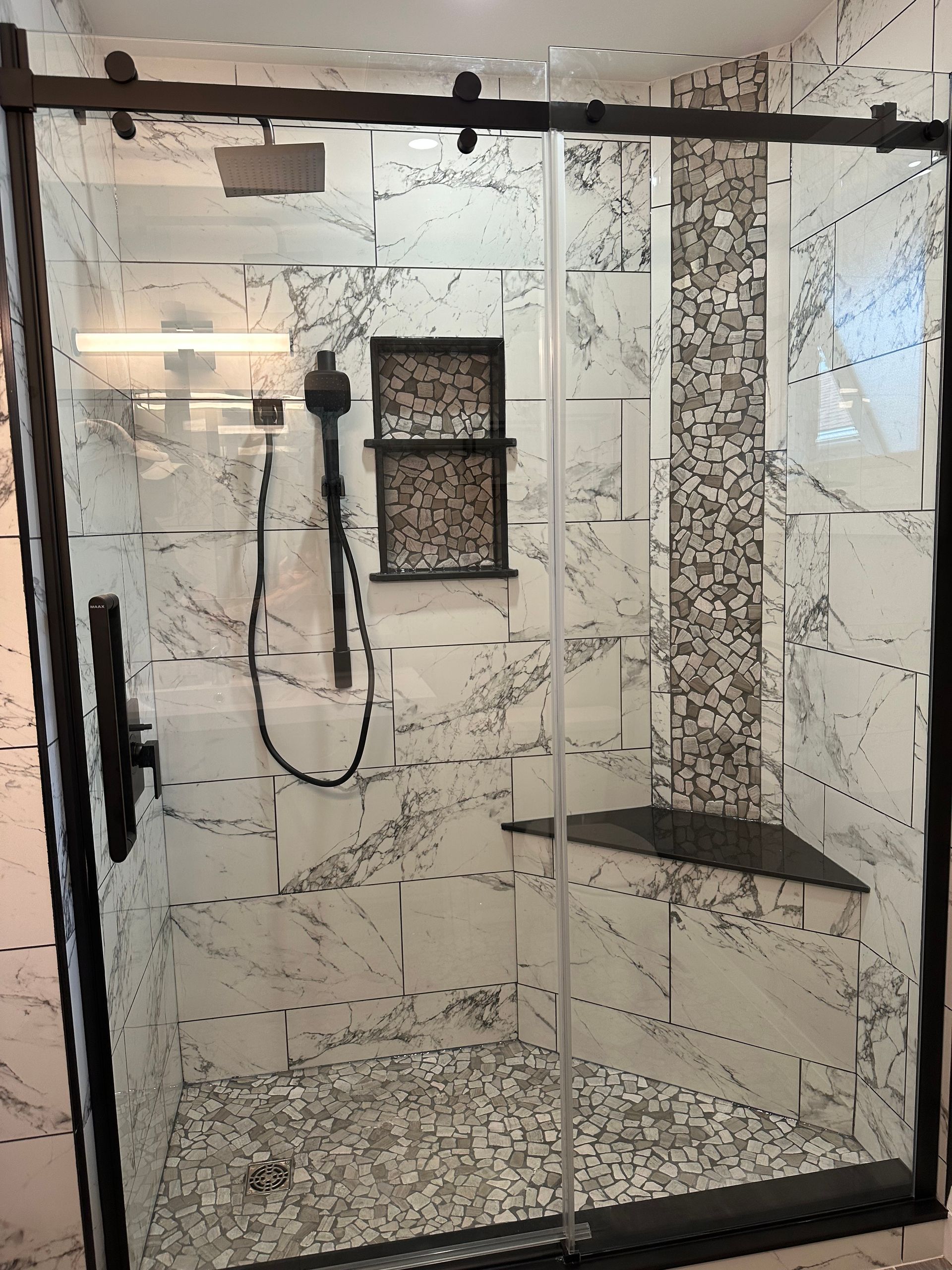 A shower with a sliding glass door and a shower head.