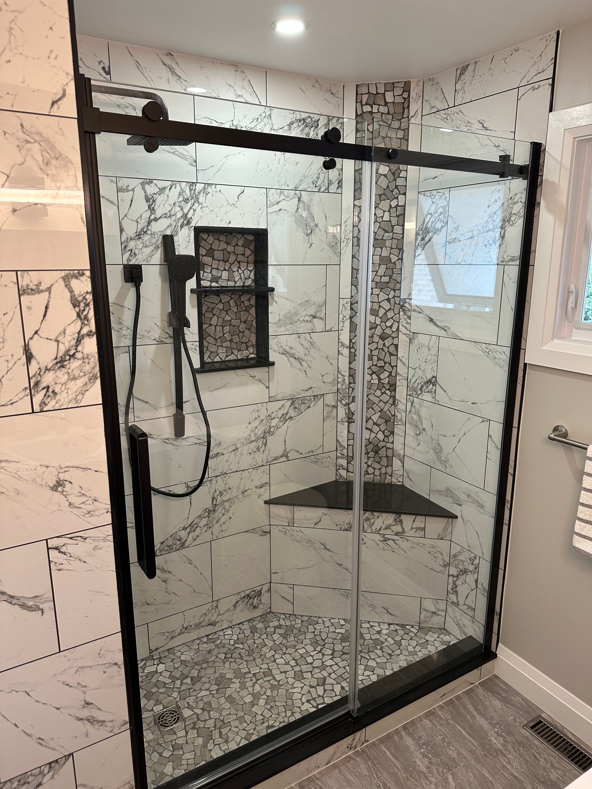 A bathroom with a sliding glass shower door and marble walls.