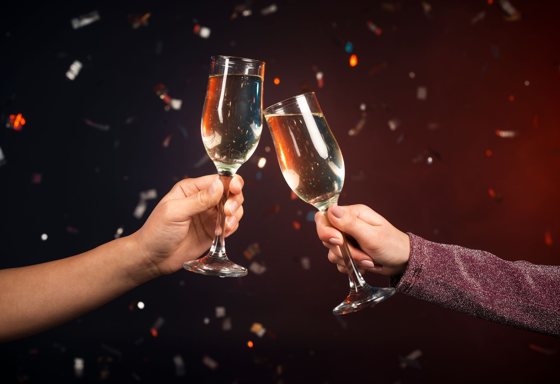 two people toasting with champagne glasses with confetti falling in the background