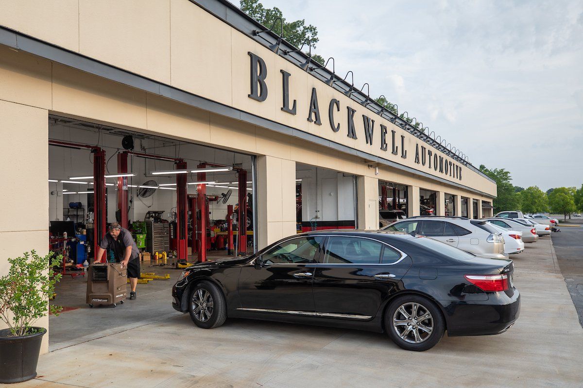 A black car is parked in front of a car dealership.