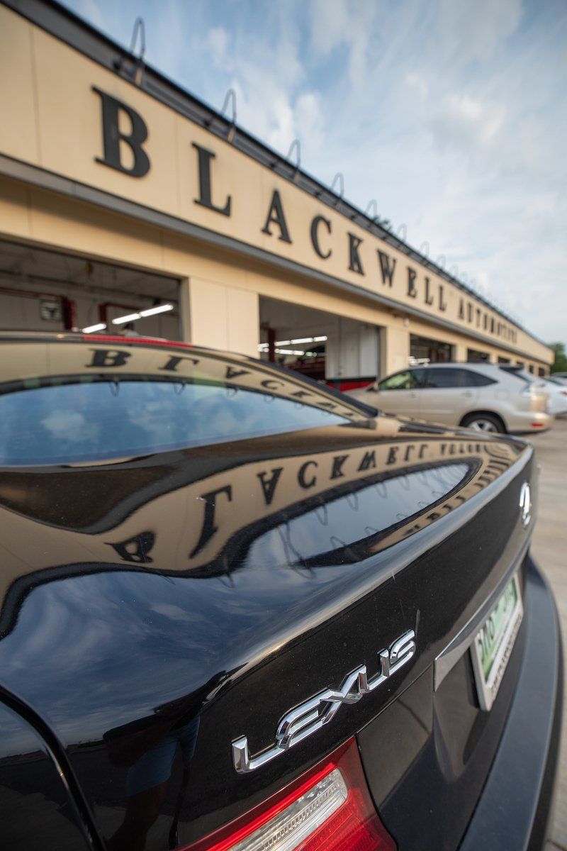 A black lexus is parked in front of a building that says blackwell auto