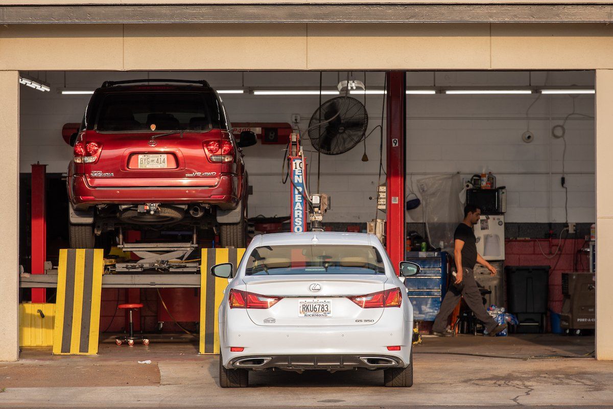 Two cars are sitting on a lift in a garage.