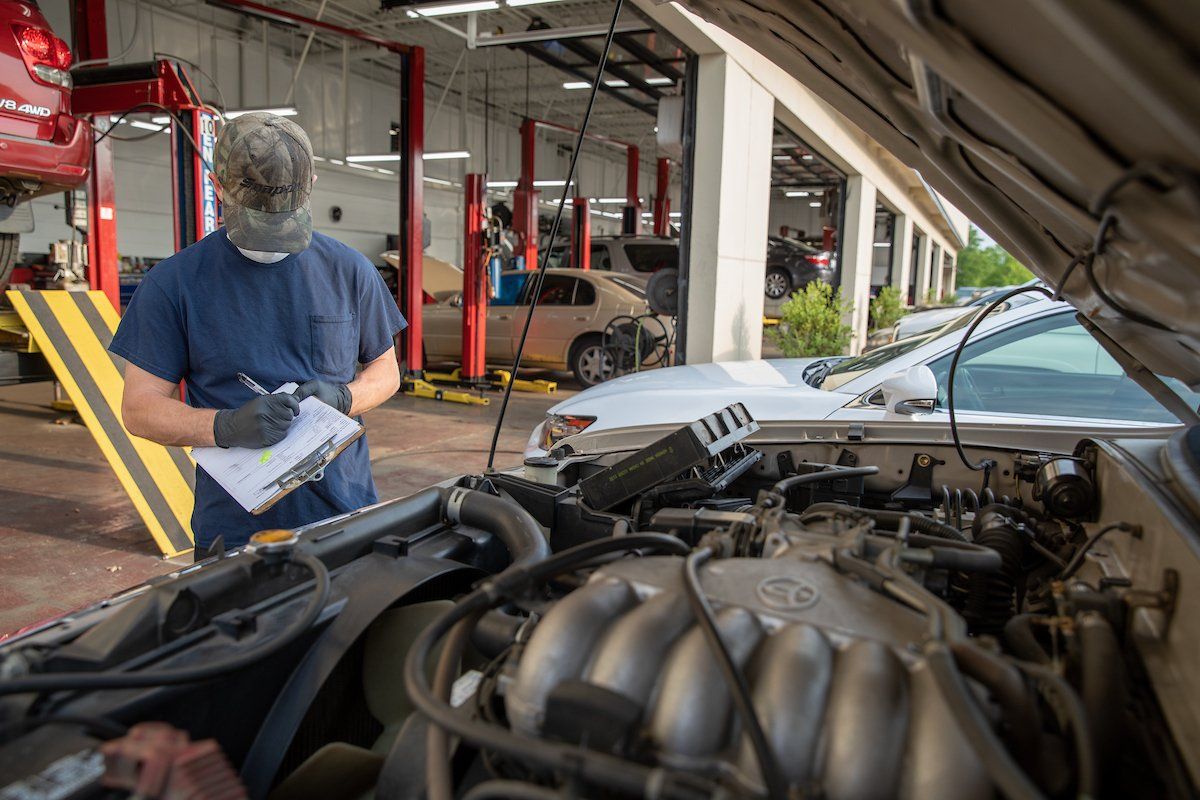 A man is working on the engine of a car in a garage.