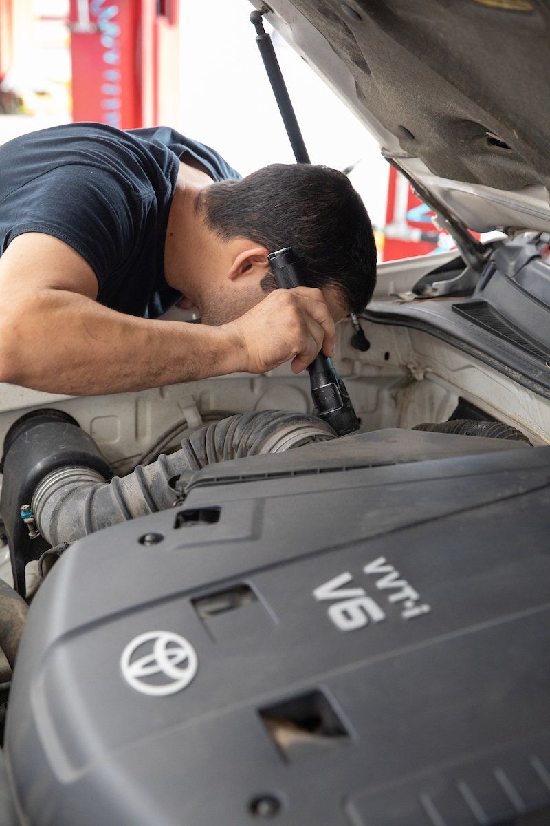 A man is working on the engine of a toyota car
