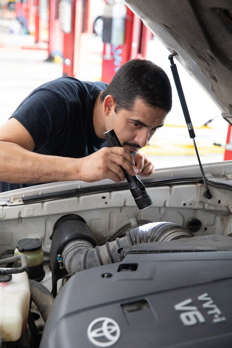 A man is working under the hood of a toyota vehicle