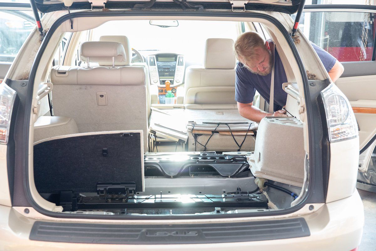 A man is working on the trunk of a car.